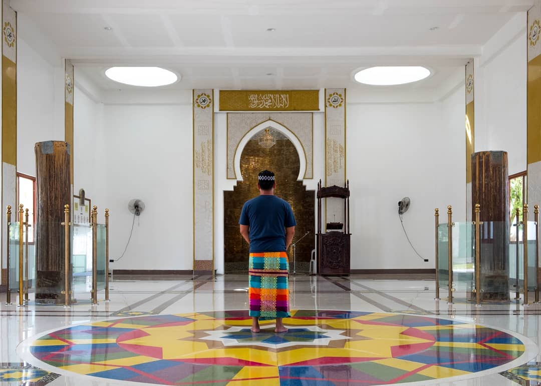 Two of the mosque’s four original wooden pillars, pictured on either side of a worshipper.