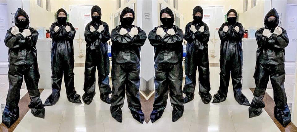men in black hazmat suits, with their fists across the chest