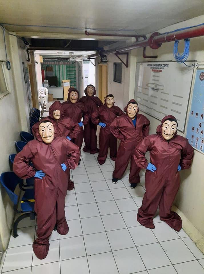 health workers in maroon hazmat suits and Salvador Dali masks