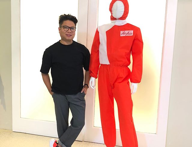 man standing beside a mannequin in a red hazmat suit