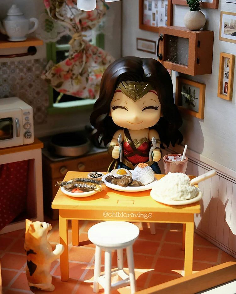 a miniature Wonder Woman figure eating mini tapsilog and tuyo