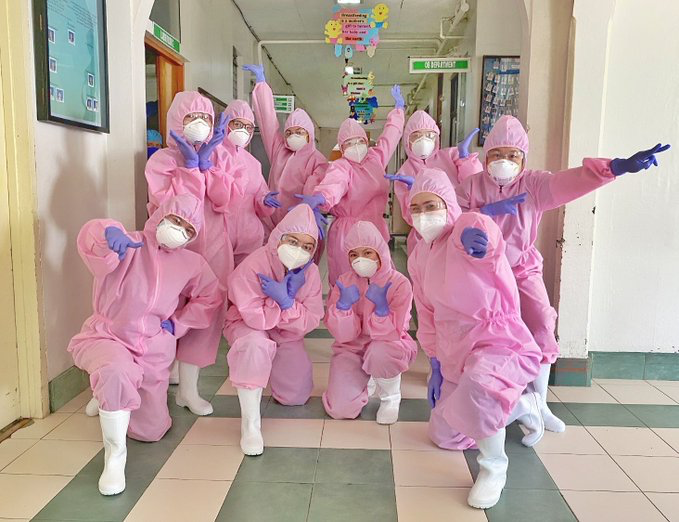 health workers in pink hazmat suits and purple gloves