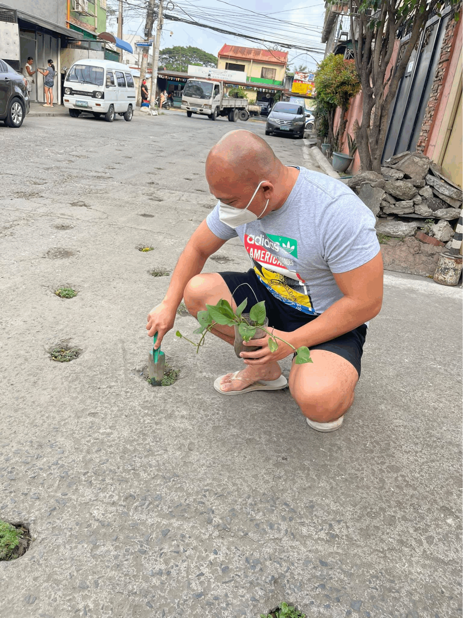 Quezon City plantito - Glenn Cui Infante placing plants in holes 